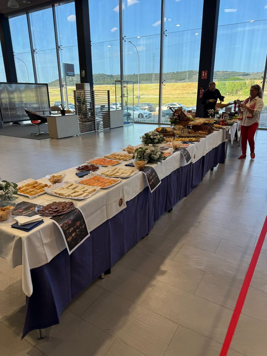 Buffet de catering de San Remo montado ante el ventanal de un concesionario, con bandejas de salmón, embutidos y quesos